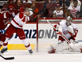 Detroit goalie Jimmy Howard, right, makes a save as Niklas Kronwall is checked by Phoenix's Chris Brown, left, in the first period Thursday, April 4, 2013, in Glendale, Ariz. (AP Photo/Ross D. Franklin)