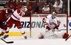 Detroit goalie Jimmy Howard, right, makes a save as Niklas Kronwall is checked by Phoenix's Chris Brown, left, in the first period Thursday, April 4, 2013, in Glendale, Ariz. (AP Photo/Ross D. Franklin)