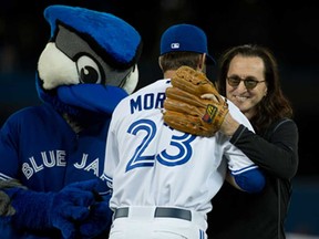 Geddy Lee, right, from the band Rush hugs Blue Jays starting pitcher Brandon Morrow after throwing the first pitch at Rogers Centre in Toronto April 2, 2013. (Tyler Anderson/National Post)