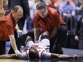 Kevin Ware #5 of the Louisville Cardinals talks with teammate Luke Hancock #11  as Ware is tended to by medical personnel after he injured his leg in the first half against the Duke Blue Devils during the Midwest Regional Final round of the 2013 NCAA Men's Basketball Tournament at Lucas Oil Stadium on March 31, 2013 in Indianapolis, Indiana.  (Photo by Andy Lyons/Getty Images)