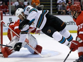 San Jose's Joe Thornton, centre, is tripped up in front of Detroit Red Wings goalie Jimmy Howard during the first period in Detroit, Thursday, April 11, 2013. (AP Photo/Carlos Osorio)
