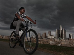 Nithin George rides along the waterfront as thunderstorms approach. (DAX MELMER/ THE WINDSOR STAR)