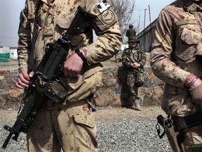 In this file photo, Canadian soldiers stand guard as an Afghan soldier, background, attends a graduation ceremony at a military training center in Kabul, Afghanistan, March 14.