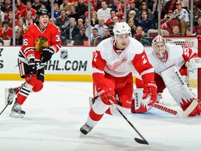 Detroit's Brendan Smith, centre, skates after the puck with Chicago's Dave Bolland, left, in front of goalie Jimmy Howard at the United Center. (Photo by Bill Smith/NHLI via Getty Images)