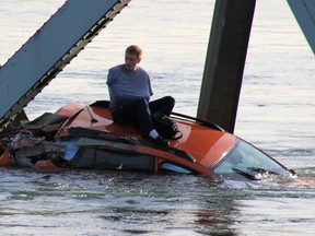 In this photo provided by Francisco Rodriguez, a man is seen sitting atop a car that fell into the Skagit River after the collapse of the Interstate 5 bridge there minutes earlier Thursday, May 23, 2013, in Mount Vernon, Wash. (AP Photo/Francisco Rodriguez)