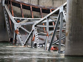 A car, lower right, and what is believed to be a travel trailer lie in the Skagit River with debris from the collapsed portion of the Interstate 5 bridge Friday, May 24, 2013, in Mount Vernon, Wash. A truck carrying an oversize load struck the four-lane bridge on the major thoroughfare between Seattle and Canada, sending a section of the span and two vehicles into the Skagit River below Thursday evening. All three occupants suffered only minor injuries. At an overnight news conference, Washington State Patrol Chief John Batiste blamed the collapse on a tractor-trailer carrying a tall load that hit an upper part of the span. (AP Photo/Elaine Thompson)