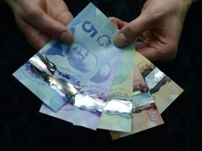 A representative with the Bank of Canada displays the new polymer $5 and $10 bank notes alongside the $20, $50, and $100 during a press conference at the Bank of Canada in Ottawa on Tuesday, April 30, 2013. (Photograph by: Sean Kilpatrick , The Canadian Press)