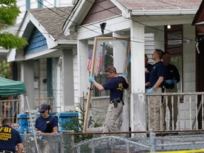 In this Tuesday, May 7, 2013 file photo, members of the FBI evidence response team carry out the front screen door from the house where three women were held captive, in Cleveland. Cleveland officials are trying to keep the house intact until the trial of the women's suspected abductor is concluded. (AP Photo/Tony Dejak, File)
