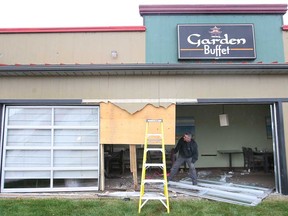 Workers with Belfor Property Restoration temporarily cover a smashed out window, Thursday, May 23, 2013, at the Garden Buffet restaurant in the 4300 block of Walker Road in Windsor, Ont. The driver of a Jaguar smashed through the window ending up inside the dining area.  (DAN JANISSE/The Windsor Star)