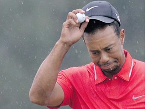 Tiger Woods dodges raindrops after putting on the final green at the 77th Masters golf tournament at Augusta National Golf Club last month. He also dodged disqualification after officials called a two-stroke penalty for an illegal drop at the 15th hole.
(Photograph by: Getty Images Files , The Associated Press)