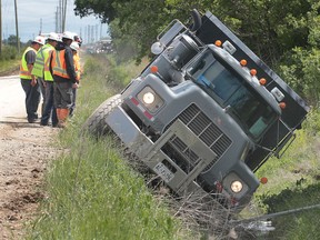 Workers check out a dump truck that slid into a ditch at the Herb Gray Parkway near Howard Avenue and Highway 401. The accident occurred approximately 11:00 a.m. No injuries were reported. The Ministry of the Environment was called in the investigate. (DAN JANISSE/The Windsor Star)