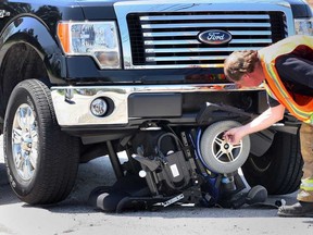 Windsor Fire Capt. Mike Woods check out damage to a  motorized wheelchair which became lodged under a Ford F150 after the driver was thrown from the chair on Tecumseh Road East near Clover Avenue, Wednesday May 1, 2013.