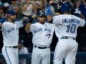 Toronto's Edwin Encarnacion, right, celebrates with Blue Jays teammates Jose Bautista, left, and Melky Cabrera after hitting a grand slam against the Baltimore Orioles in the sixth inning Thursday. (THE CANADIAN PRESS/Nathan Denette)