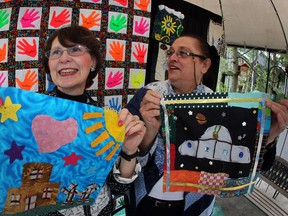 Ann Mueller and Barbara Kersey hold quilt panels created by students from McCallum, Campbell, AV Graham, St. John Vianney, Harrow and Taylor schools, April 30, 2013.  Behind, a recently sewn quilt by Mueller, made of hand panels which date to the 1991-92 Eastwood Public grade two class, is displayed. (NICK BRANCACCIO/The Windsor Star)