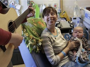 Music therapist Elizabeth Klinger, left, quietly plays guitar and sings for Henry Buchert and his mother Stacy Bjorkman, in the Pediatric Intensive Care unit at Ann & Robert H. Lurie Children's Hospital in Chicago on Monday, May 6, 2013.(M. Spencer Green/The Associated Press)