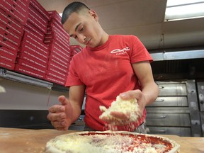 Mario Kotiach, an employee at Capri Pizza on Dougall Ave. in Windsor, Ont. makes a pizza Friday, May 3, 2013. The provincial budget is going to give pizza businesses a break on the price of cheese. (DAN JANISSE/The Windsor Star)