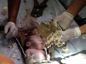 In this still image taken from video from Saturday May 25, 2013, rescue workers cut away parts of a sewage pipe where a newborn baby was trapped in Pujiang in east China's Zhejiang province. Chinese firefighters have rescued a newborn boy from a sewer pipe below a squat toilet, sawing out an L-shaped section and then delicately dismantling it to free the trapped baby, who greeted the rescuers with cries. A tenant heard the baby’s sounds in the public restroom of a residential building in Zhejiang province in eastern China on Saturday and notified authorities, according to the state-run news site Zhejiang News. A video of the two-hour rescue that followed was broadcast widely on Chinese news programs and websites late Monday and Tuesday. (AP Photo)