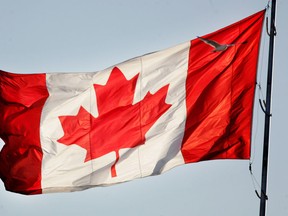 A large back-lit Canadian flag flutters in this file photo. (MIKE CARROCCETTO/ The Ottawa Citizen)