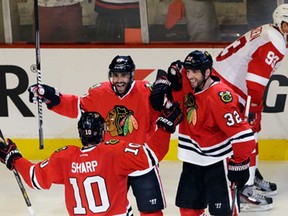 Chicago's Johnny Oduya, centre, celebrates with teammates Michal Rozsival, right, and Patrick Sharp after scoring a goal as Detroit's Johan Franzen reacts during Game 1 of the Western semifinal in Chicago, Wednesday, May 15, 2013. (AP Photo/Nam Y. Huh)