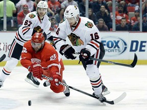 Detroit's Carlo Colaiacovo, centre, tries to clear the puck from Chicago's Marcus Kruger, right, during Game 6 of the Western Conference semifinal in Detroit, Monday, May 27, 2013. (AP Photo/Paul Sancya)