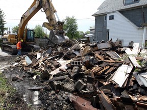 An excavator knocks down the remains of a vacant house at 859 Assumption St. that was destroyed by fire early May 17, 2013. (Nick Brancaccio / The Windsor Star)