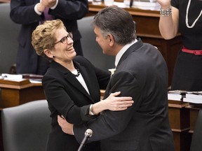 Ontario Finance Minister Charles Sousa, right, receives a hug from Ontario Premier Kathleen Wynne after tabling the 2013 provincial budget. THE CANADIAN PRESS/Nathan Denette