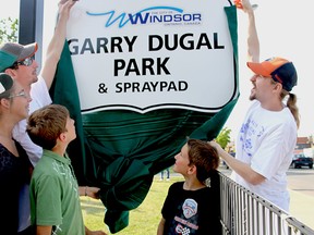 Brothers Gary, left, and Joe Dugal, along with family, unveil the new sign to a park on Drouillard Road that was renamed Saturday in honour of their father, Garry Dugal, a Ford City community organizer who died last summer. Hundreds attended the renaming ceremony at the former Drouillard Park. (REBECCA WRIGHT/ The Windsor Star)