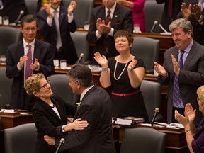 Ontario premier Kathleen Wynne (left bottom) embraces Minister of Finance Charles Sousa after he delivered the provincial budget on behalf of Ontario's minority Liberals at Queens Park in Toronto, Ontario, May 2, 2013.  Local Liberal MPP Teresa Piruzza stands clapping in the centre.(Tyler Anderson/National Post)