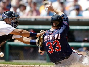 Minnesota's Justin Morneau, left, scores as Detroit catcher Brayan Pena misplays the throw from left fielder Matt Tuiasosopo during the first inning in Detroit Wednesday, May 1, 2013. Morneau scored from second on an RBI single by Chris Parmelee. (AP Photo/Carlos Osorio)