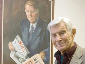 Peter Worthington poses in 2011 in front of a portrait of friend and Toronto Sun co-founder Doug Creighton. (Jack Boland/The Canadian Press)