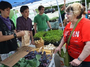 In this file photo, Gwen Pelerose Power buys some popcorn on the cob from Caleb Vegh and John Kosty at the Downtown Windsor Farmers' Market on its opening day at Charles Clark Square, Saturday, June 1, 2013.  (DAX MELMER/The Windsor Star)