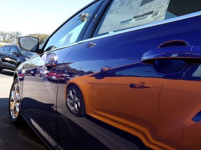 A Ford Focus is reflected on the side of another Focus in a new car lot. (Getty Images files)
