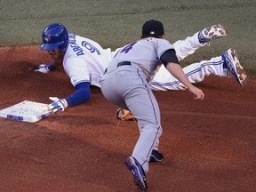 Toronto's J.P. Arencibia, left, slides into second base safely after hitting an RBI double in the first inning as Josh Rutledge of the Rockies attempts to tag him Tuesday at Rogers Centre. (Photo by Tom Szczerbowski/Getty Images)