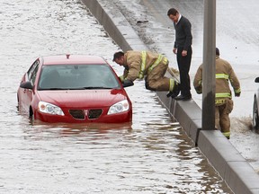 Driver Alexander Gonzalez stands on a jersey barrier after being rescued from his car by firefighters after it stalled trying to cross a deep lake flooding northbound Crowchild Trail near near 26th avenue S.W. on Sunday April 17, 2011. The flooding was believed to be the result of a broken water main in the area. (Gavin Young/Calgary Herald)