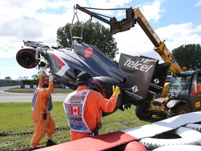 Track workers remove the car of Sauber driver Esteban Gutierrez of Mexico after a crash at the Canadian Grand Prix, Saturday, June 8, 2013 in Montreal. A worker was killed when he was run over by the tractor. (THE CANADIAN PRESS/Tom Boland)