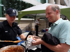 Windsor police Const. Leigh-Ann Godwin serves a heaping ladle of chili onto Windsor Star reporter Craig Pearson's hot dog during the Windsor Police Community Services Fundraising event for Camp Brombal on June 21, 2013. Hot dogs were sold along Chatham Street east and donations were collected to send area grade 6 students to camp this summer. (DYLAN KRISTY/The Windsor Star)