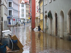 A woman walks through rhe flooded street can be seen in Meissen after the River Elbe causing massive flooding in the area on June 9, 2013. Parts of northern Germany continued to be threatened by the swollen River Elbe where a dyke was breached overnight in Saxony-Anhalt state, adding hundreds to the already thousands of German residents to have been evacuated. AFP PHOTO / ARNO BURGI