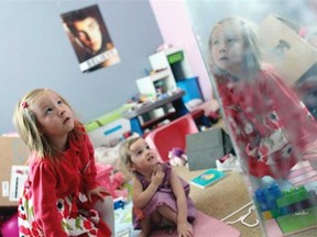 With her face reflected in a mirror, Coy Mathis, left, a transgender girl, plays with her sister, Auri, 2, centre, at their home in Fountain, Colo., on Monday, Feb. 25, 2013. Coy is returning to school after winning the right to use the girl’s bathroom (Brennan Linsley , The Associated Press)