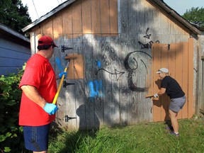 Our West End volunteer Steve Symons, left, and Chrysler Canada employee Dawn Bizaire paint over graffiti along a fence near the 600 block of MacEwan Avenue in Windsor, Ontario on June 26, 2013. Nearly a hundred Chrysler Canada office volunteers worked together with the United Way of Windsor/Essex County and OWE to brighten up several area parks in Windsor's west-end neighbourhoods. Employees will brave the heat to clean, trim, paint and weed these parks that are enjoyed by thousands of area residents and visitors. Chrysler Group's Community Action Day encourages volunteerism and community involvement. An estimated 400 volunteer hours, 80 gallons of paint, 50 sanding sponges, countless yard waste bags, work gloves and trimming tools will be used to help brighten up the community parks. (JASON KRYK/The Windsor Star)