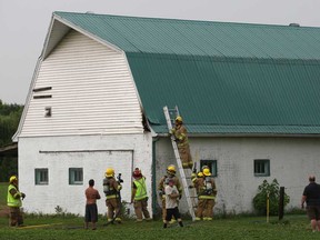 Firemen with Lakeshore Fire and Rescue deal with a hot spot on the side of a barn at a home on County Road 2, east of Belle River, Saturday, June 22, 2013.  A lightning strike is believed to be the cause.  (DAX MELMER/The Windsor Star)