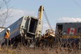 A person working at the VIA Rail derailment site walks past a passenger car off the tracks in Burlington, Ont., on February 27, 2012. The Transportation Safety Board says the operating crew of a Via Rail train which derailed west of Toronto last year "misperceived" crucial signals telling them to slow down before the fatal crash. THE CANADIAN PRESS/Pawel Dwulit