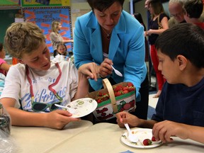 MPP Teresa Piruzza delivers fresh strawberries to students Hunter Pitre, left, and Michael Toma at St. John Vianney School during an event highlighting the Ontario School Nutrition Program, Friday June 21, 2013. (NICK BRANCACCIO/The Windsor Star)