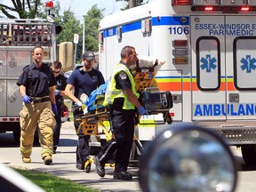WINDSOR, ONTARIO- JUNE 20, 2013 -  Windsor EMS paramedics, Windsor firefighters, and Windsor Police assist in rushing a man to a waiting ambulance after an electrical accident while trimming a tree near Lillian Avenue and Vanier Street in Windsor, Ontario. (JASON KRYK/The Windsor Star)
