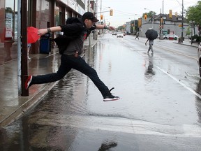 Rob Gaines takes a giant step off the curb as he and hundreds of other pedestrians try to navigate around a large pond of rainwater on Wyandotte Street West at Ouellette Avenue Friday June 28, 2013. (NICK BRANCACCIO/The Windsor Star)