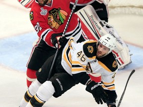 Chicago's Michal Rozsival, centre, checks Boston's David Krejci in front of goalie Corey Crawford in Game 5 Saturday. (Photo by Jamie Squire/Getty Images)