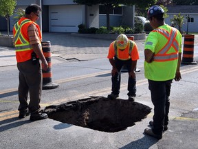 Mike Mazza, left, of City of Windsor Public Works were joined by Danruss Contractors and Union Gas on Riverside Drive East at Watson Avenue where a wide sink hole opened up on the east bound lane Monday June 24, 2013.  (NICK BRANCACCIO/The Windsor Star)