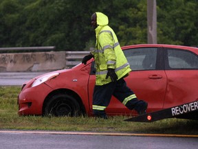 Myers Towing operator Rick Bryant battles a downpour while preparing to tow a vehicle from the median of EC Row Expressway Tuesday June 25, 2013. Windsor Police were on the scene to make a report and assist with traffic. (NICK BRANCACCIO/The Windsor Star)