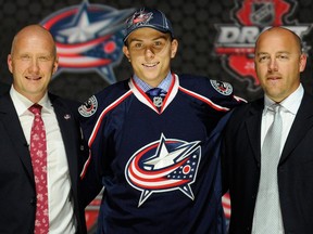 Tecumseh's Kerby Rychel, centre, stands with Columbus Blue Jackets GM Jarmo Kekalainen, left, after being chosen 19th overall in the first round of the NHL hockey draft Sunday in Newark, N.J. (AP Photo/Bill Kostroun)