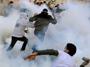 An Egyptian protester prepares to hurl a tear gas canister back at security forces as others run for cover on the third day of clashes at Tahrir Square in Cairo on November 21, 2011.(AFP/Getty Images/ Mohammed Hossam)