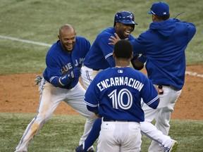 Toronto's Rajai Davis, centre, is congratulated by Emilio Bonifacio and Esmil Rogers after driving in the winning run in the 18th inning against the Texas Rangers Saturday at Rogers Centre in Toronto. (Photo by Tom Szczerbowski/Getty Images)